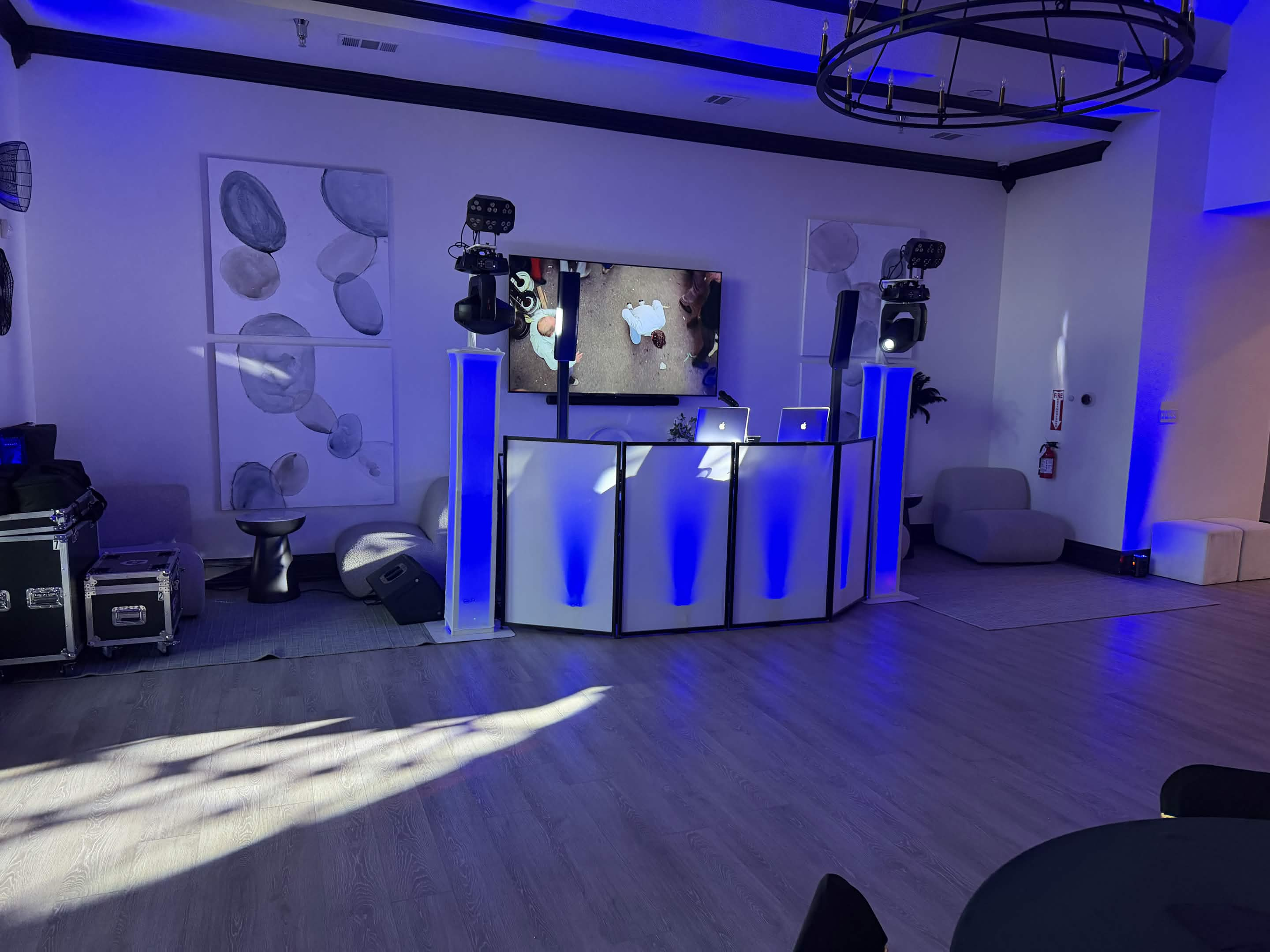Modern lounge DJ booth with blue lighting, speakers, and moving lights